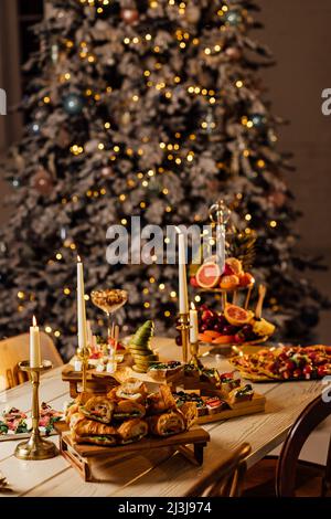 beautifully decorated Christmas table with candles and glasses near the Christmas tree. Stock Photo