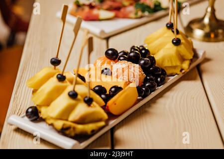 Pineapple fruit cut on wooden.festive table setting with candles for wedding party in the dark. Stock Photo