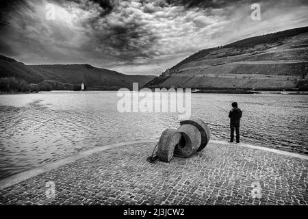 Rhine-Nahe corner near Bingen in winter, sky with dramatic mood, sculpture Poseidon and angler in foreground, black and white, Stock Photo