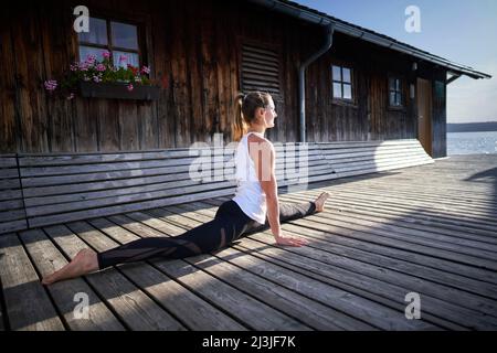Woman doing yoga exercise at lido Utting am Ammersee, Bavaria, Germany Stock Photo