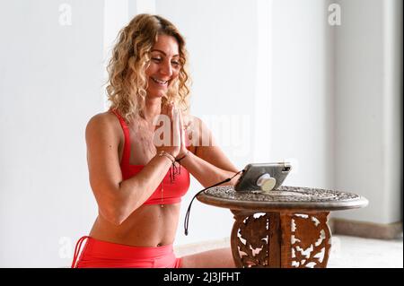 Fitness coach teaching yoga online to group of people. People practicing yoga with trainer via video conference Stock Photo