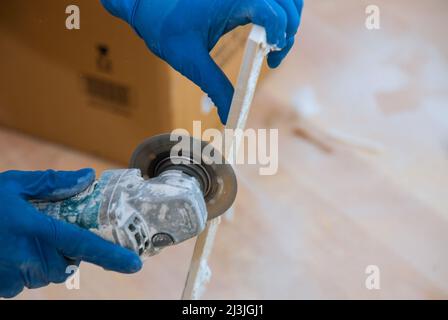 Construction site with worker cutting a tile using an circular saw Stock Photo