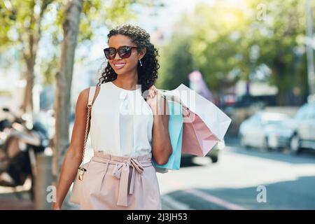 Adding items to my closet. Shot of an attractive young woman going shopping in the city. Stock Photo