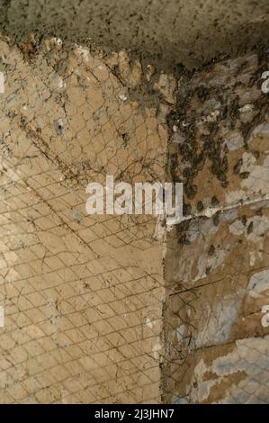 The master throws a solution of liquid concrete on the wall, the first layer of plaster on the wall, metal mesh attached to a wooden wall. Stock Photo