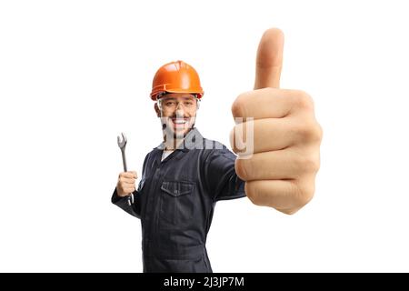 Worker in a uniform with helmet holding showing a thumb up gesture isolated on white background Stock Photo