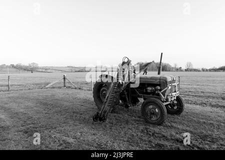 An old antique hedge trimmer mounted on a vintage tractor Stock Photo