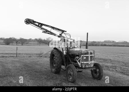 An old antique hedge trimmer mounted on a vintage tractor Stock Photo