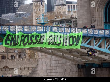 London, UK. 8th Apr, 2022. Police talk to activists from Extinction Rebellion as they hang from suspension cords beside a giant banner that reads ‘End fossil fuels now', during a protest on Tower Bridge. Credit: ZUMA Press, Inc./Alamy Live News Stock Photo