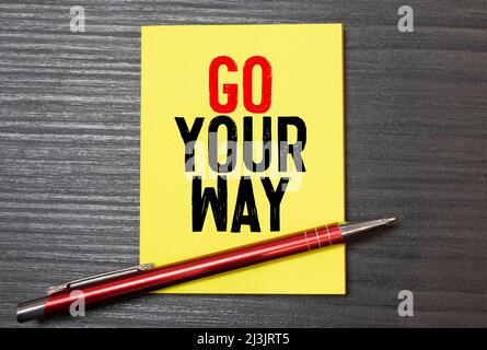 yellow sticker inscription Go your own way attached blue magnet white fridge. close-up Stock Photo