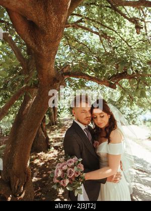 Happy wedding couple walking in a botanical park grain effect authentic Stock Photo