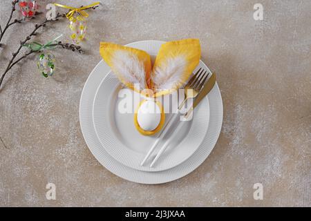 Beautiful festive Easter table setting with plates and napkin Easter Bunny, willow twig, top view, copy space Stock Photo