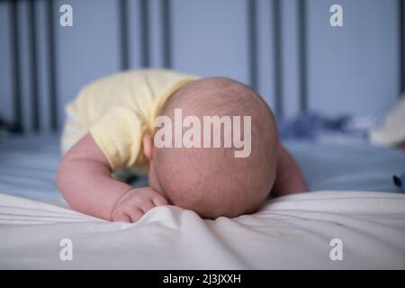 Baby is laying down and sleeps on bed. Having a nap after palying games. Stock Photo