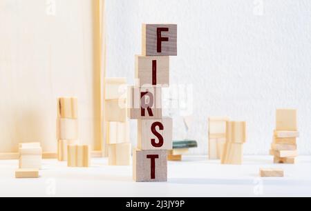 word first written with black letters on small wooden blocks against bright yellow background at light closeup. Stock Photo