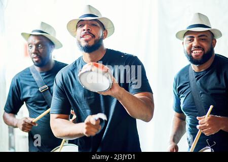 Let the beat take you on a journey. Cropped shot of a group of handsome young male drummers playing at Carnival. Stock Photo
