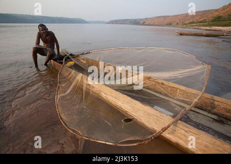 A Congolese fisherman in a traditional pirogue or dug out canoe.; Lower Zaire River, near Pioka, Democratic Republic of the Congo. Stock Photo