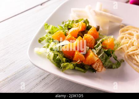 Fresh mixed lettuce and tangerine salad, accompanied by jicama 'Pachyrhizus erosus' also known as Mexican yam bean or Mexican turnip. Closeup image. Stock Photo