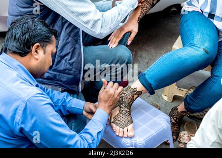 Woman getting henna tattoos (Mehndi) on hands and feet; Amritsar, Punjab, India Stock Photo