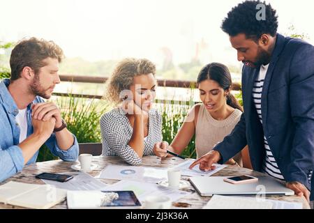 Lets explore more into this idea. Shot of a group of businesspeople having a meeting outdoors. Stock Photo