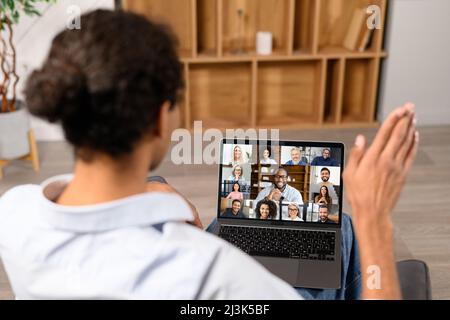 Back view millennial guy greeting diverse group of colleagues or friends, taking a part in virtual meeting. Video call, brainstorming on the distance Stock Photo
