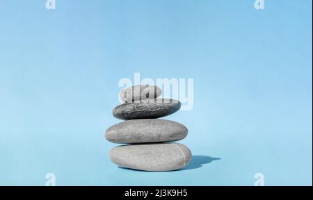 Balanced pebble stones for spa treatments on blue background. The balancing cairn - symbol of harmony, tranquility and relaxation, concept of Stock Photo