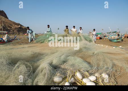 Man busy in knitting fish catching net to earn his livelihood for support  his family, on other hand fishing is ban due to rough sea, at Fishery in  Ibrahim Hyderi in Karachi