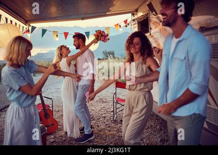 Newlywed couple in a hug, dancing. Friends around dancing. Wedding celebration in front of camper rv. Wedding, love, nature concept Stock Photo