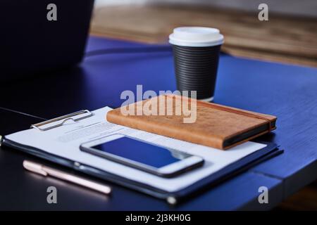 The executives toolkit. Closeup shot of a cellphone, diary and paperwork on a table in an office. Stock Photo
