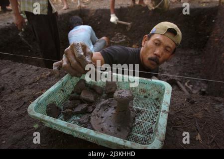 A worker collecting pottery fragments during the excavation  of prehistoric burial site conducted by the Indonesia's National Archaeology Research in Tempuran, Karawang, Indonesia. Stock Photo