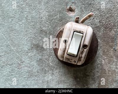 Old light power switch with tear electronic wire set on the wall. Stock Photo