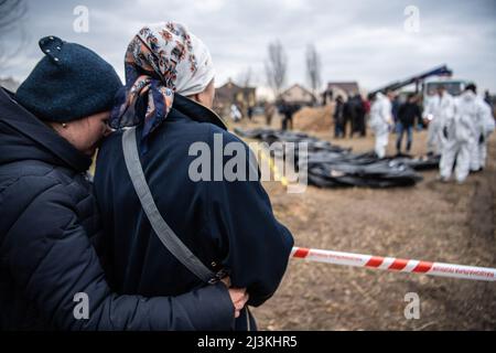 Bucha, Ukraine. 08th Apr, 2022. Women watch and embrace each other as bodies are exhumed from a mass grave and inspected by the authorities for possible war crimes in Bucha, a town near Kyiv that was recently liberated from Russian occupation. Credit: SOPA Images Limited/Alamy Live News Stock Photo