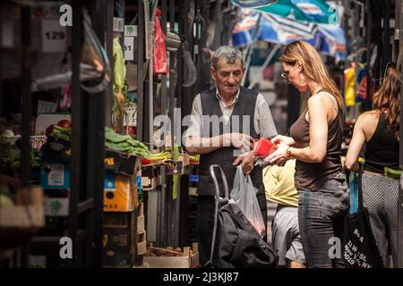 Picture of a young woman paying an old senior merchant for fruits, vegetables and food, in kaleniceva pijaca green market in belgrade center, one of t Stock Photo