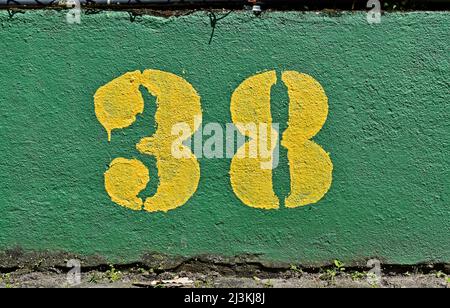 Number 38 painted in yellow on a green wall Stock Photo