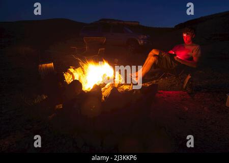 A man sitting near the campfire on the banks of a river. Stock Photo