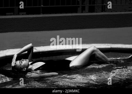 A woman relaxes in a swimming pool. Stock Photo