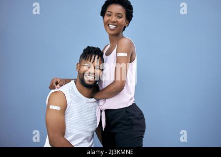 We did it together. Shot of a young couple posing together in the studio after getting their Covid vaccines. Stock Photo