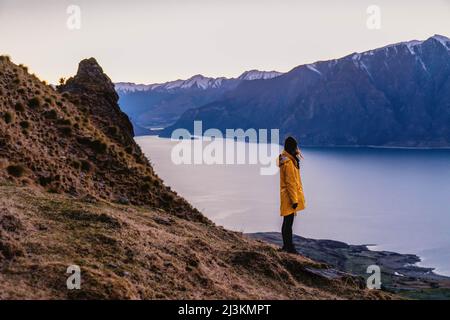 A hiker watches the sun rise over an alpine lake. Stock Photo