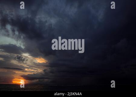 Dark and threatening storm clouds form in the sky over the ocean at sunset; Gili Trawangan, Lombok, West Nusa Tenggara, Indonesia Stock Photo