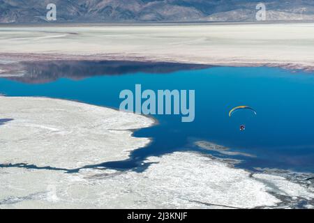 A paramotor pilot flies over Owens Lake, a mostly dry lake bed, in the Sierra Nevada near Lone Pine Stock Photo