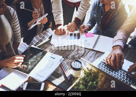 Success is all a numbers game. Cropped shot of a group of colleagues having discussing paperwork during a meeting at a cafe. Stock Photo