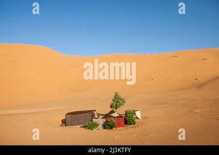 A remote tented camp is visible near a sand dune in the Sahara near Erg Chebbi; Erg Chebbi, Morocco Stock Photo