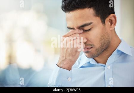 Sometimes challenges arise last minute. Shot of a businessman experiencing a headache at work. Stock Photo