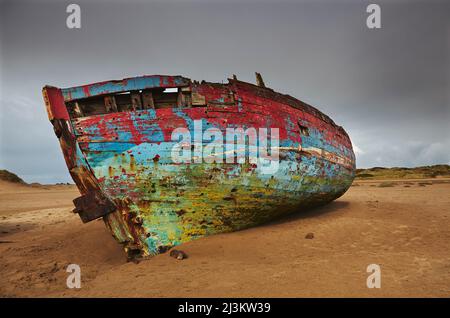Colourful weathered shipwreck lying in sand dunes at Crow Point, at the mouth of the Taw and Torridge Rivers, near Barnstaple, Devon, Great Britain Stock Photo