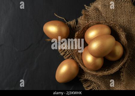 Golden easter eggs in nest bird on black background. Stock Photo