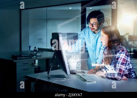 Their minds are constantly working in overdrive. Shot of two focussed young programmers working together on a computer in the office at work during Stock Photo