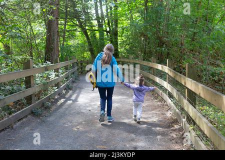 Grandmother and granddaughter having an adventure, holding hands and walking down a path together; North Vancouver, British Columbia, Canada Stock Photo