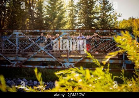 Family of seven standing on a bridge for a family portrait in a city park in autumn; Edmonton, Alberta, Canada Stock Photo