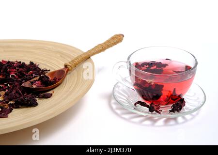 Dried leaves Sudanese rose wooden dish and cup of brewed tea on white, herbal tea karkade Stock Photo