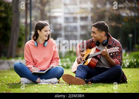 Ive been working on a song for you. Shot of two students sitting together on campus. Stock Photo