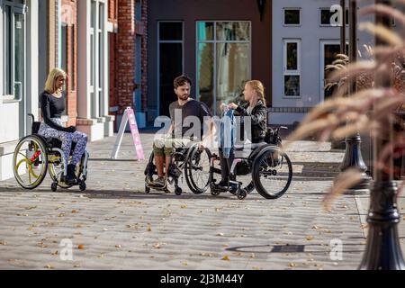 Three young paraplegic friends spending time together shopping outside in a city area; Edmonton, Alberta, Canada Stock Photo