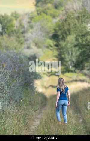 Woman walking along an old cart path in rural Saskathewan; Prince Albert, Saskatchewan, Canada Stock Photo